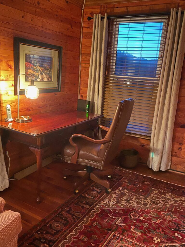 A desk and chair in the corner of a room.
