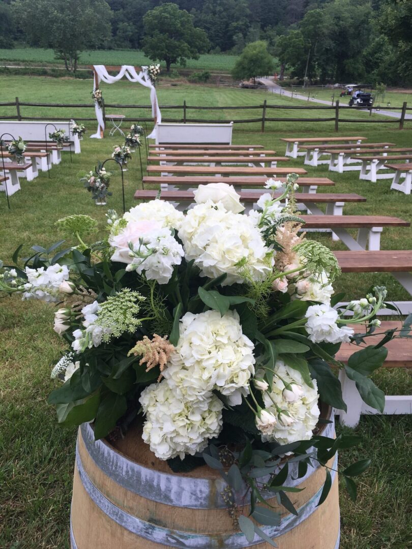 A large bouquet of flowers in the middle of an outdoor ceremony.