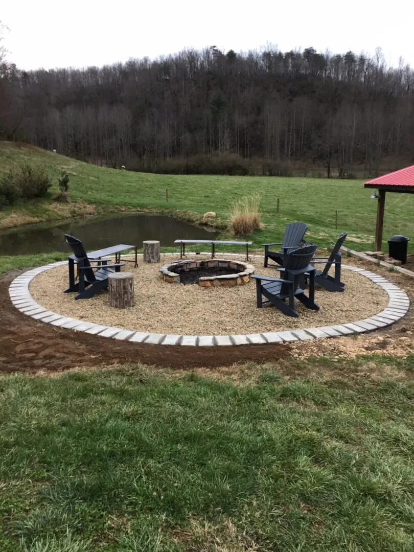 A fire pit with chairs around it in the middle of a field.