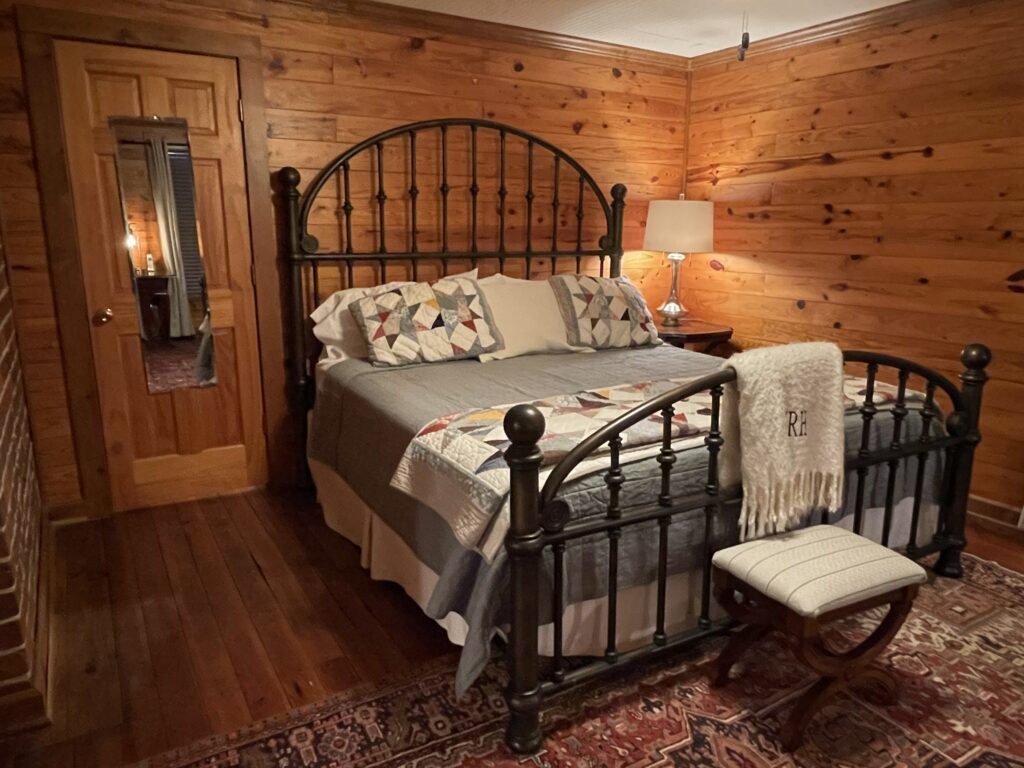 A bedroom with wood paneled walls and wooden floors.